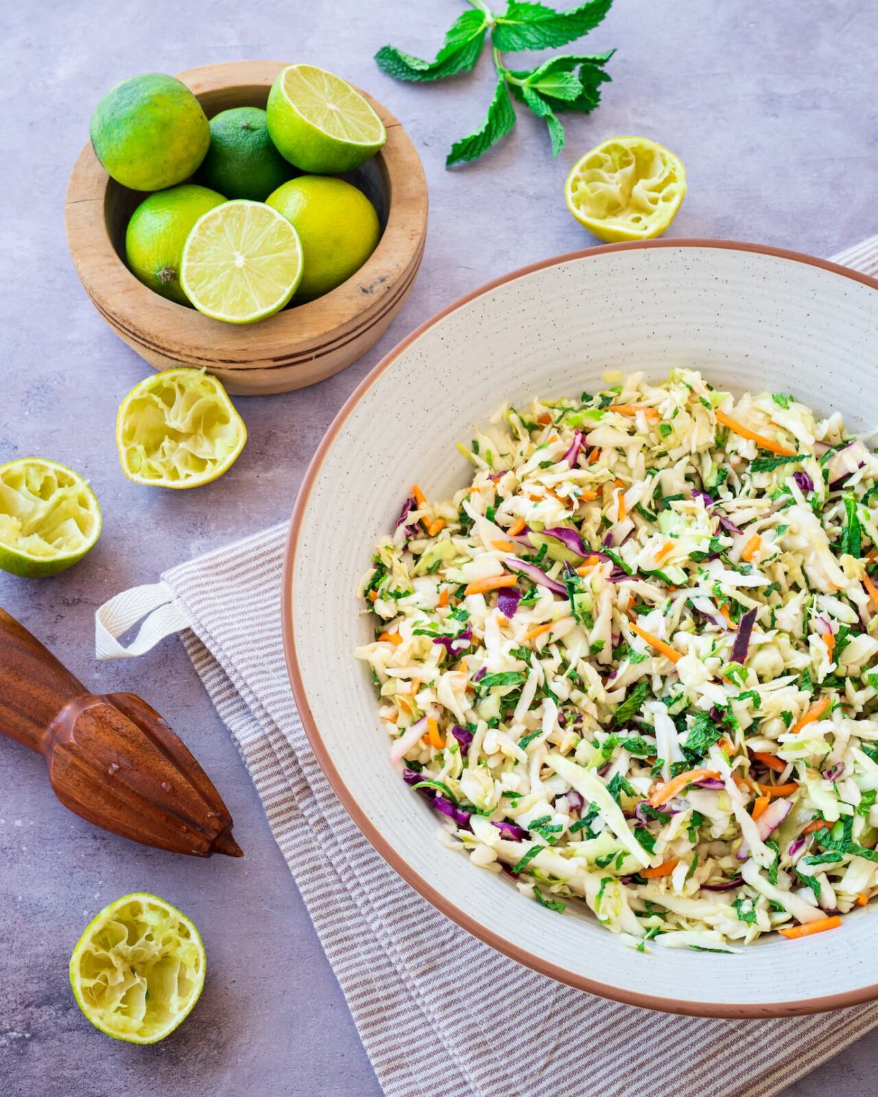Salade de chou présentée dans un bol et entourée de plusieurs limes
