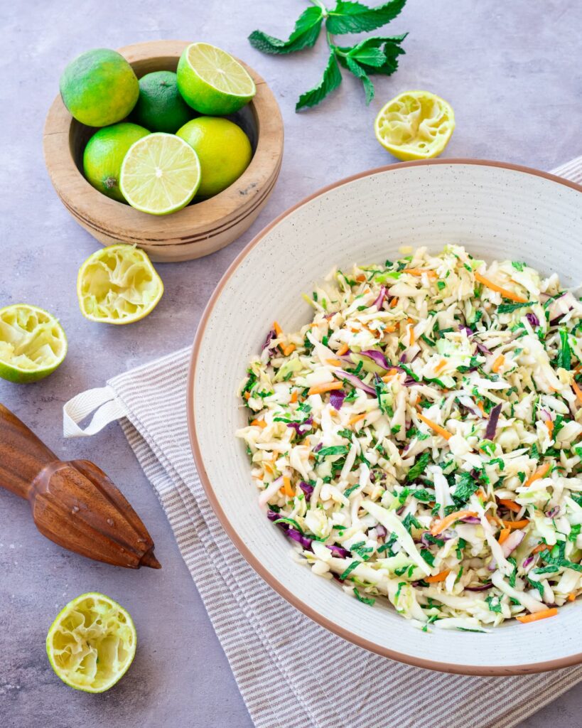 Salade de chou présentée dans un bol et entourée de plusieurs limes