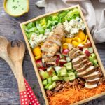 Salade de style Cobb ultra colorée et présentée dans un plateau en bois rectangulaire