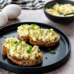 Deux tartines aux oeufs et fromage cottage déposées dans une assiette noire