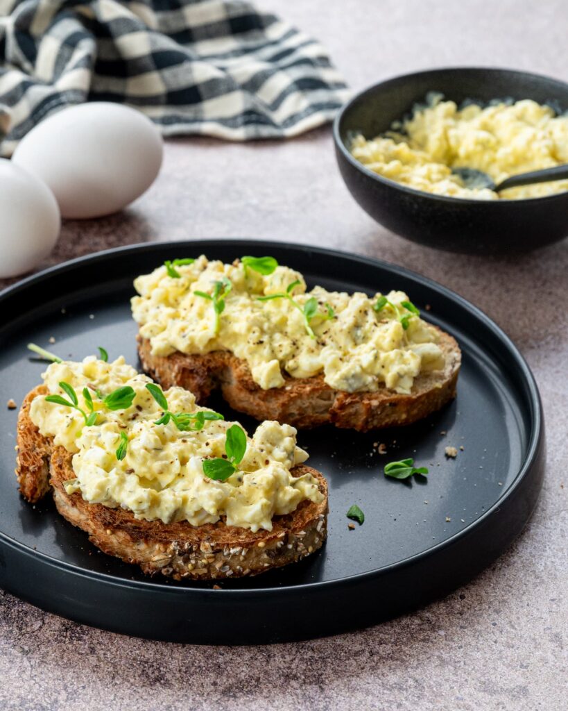 Deux tartines aux oeufs et fromage cottage déposées dans une assiette noire