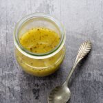 Vinaigrette polyvalente à l'huile d'avocat déposé dans un petit pot en vitre sur un fond gris