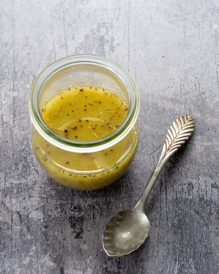 Vinaigrette polyvalente à l'huile d'avocat déposé dans un petit pot en vitre sur un fond gris