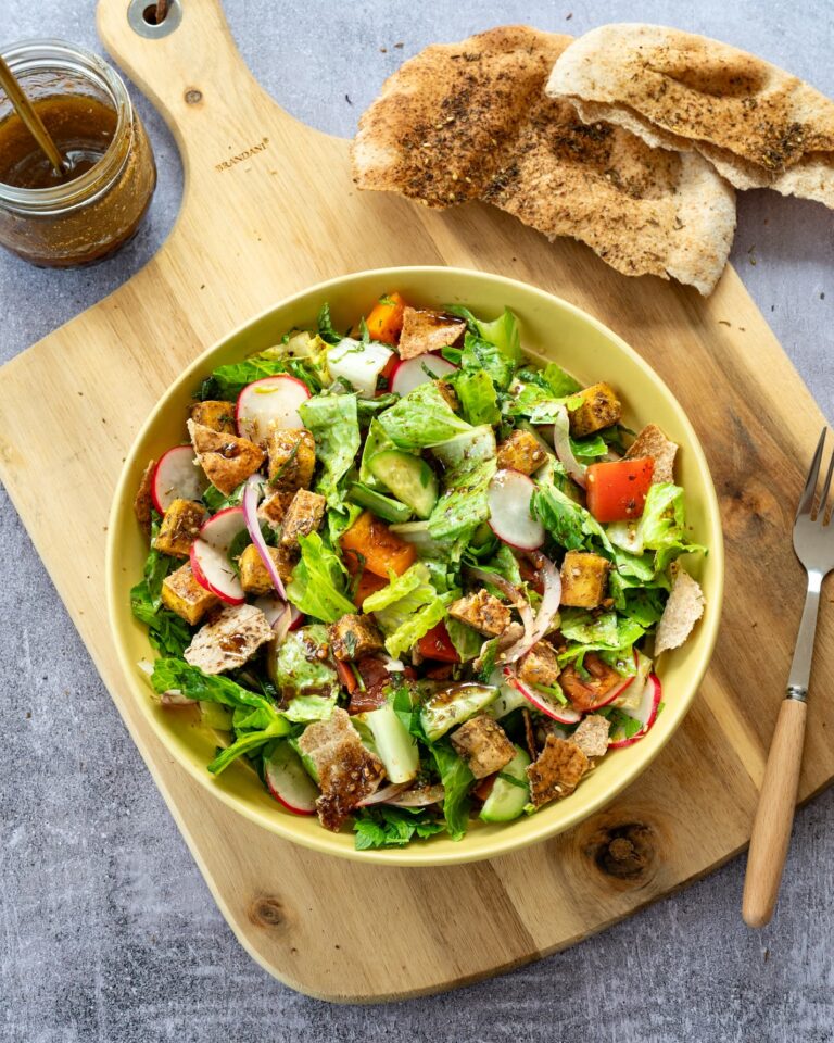 Magnifique salade fattoush avec tofu présenté dans une assiette jaune et accompagnée de pita grillé et d'une vinaigrette