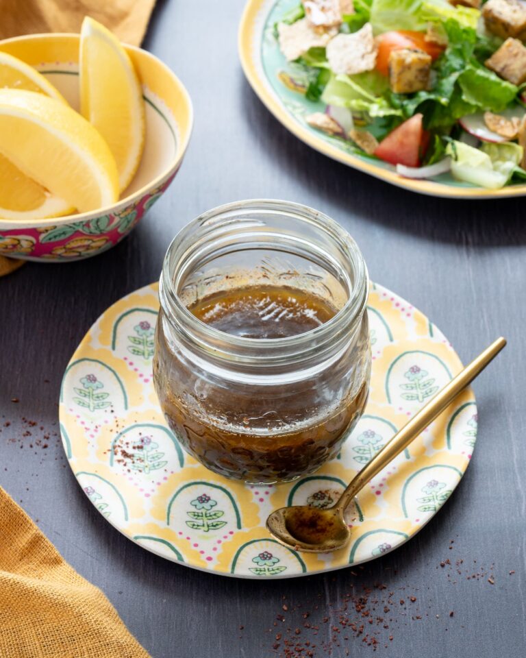 Vinaigrette au sumac déposée dans un petit pot en verre et accompagner d'une salade et de quartiers de citron