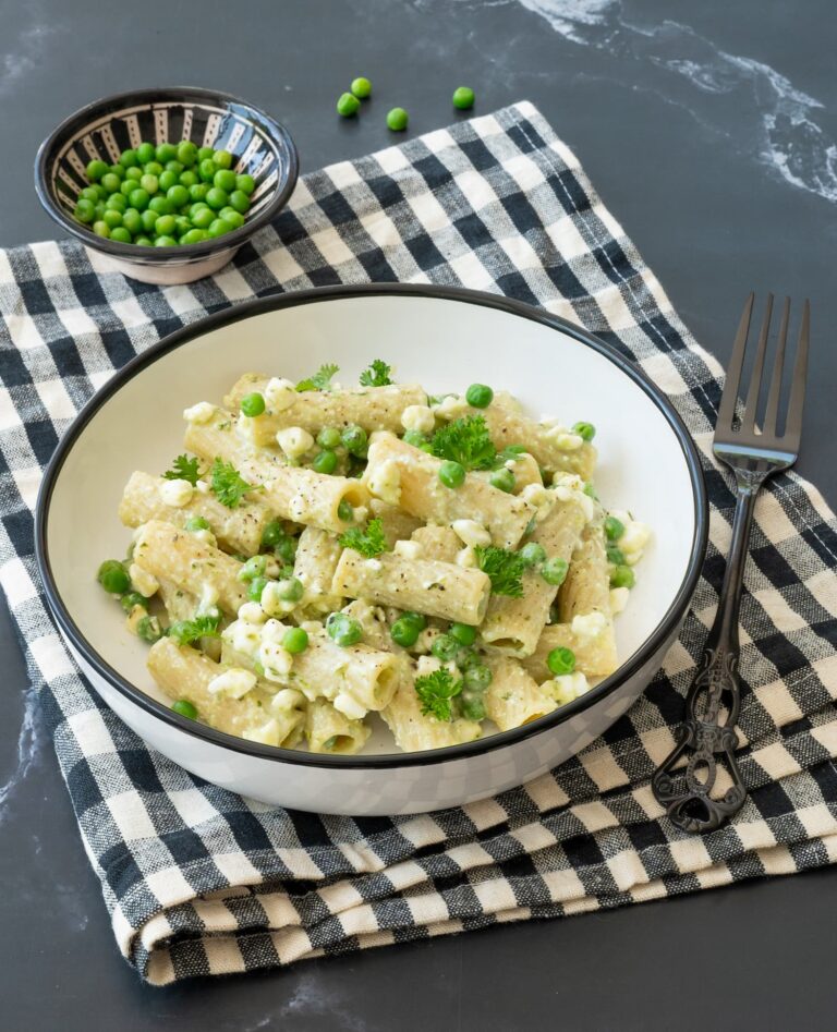 Bol de pâtes au pesto et pois verts, déposés sur un linge quadrillé noir et blanc