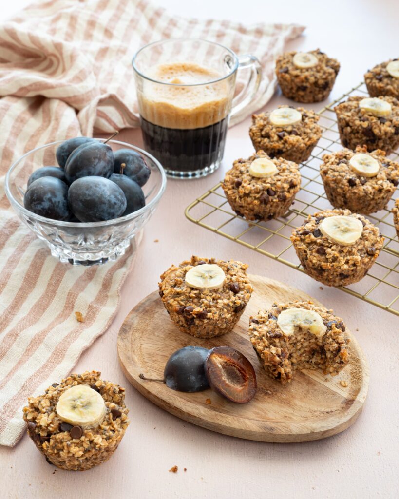 Muffins à l'avoine, bananes et chocolat déposés sur une grille de cuisson, accompagnés d'un café et de petites prunes