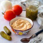 Sauce de style Big Mac déposée dans un petit bol coloré et accompagnée d'une tomate, de deux cornichons et de relish