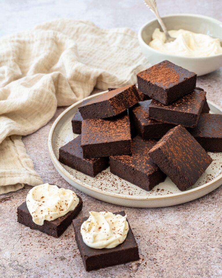 Décadent gâteau de style brownies coupés en carrés, déposés dans une assiette et saupoudrés de cacao