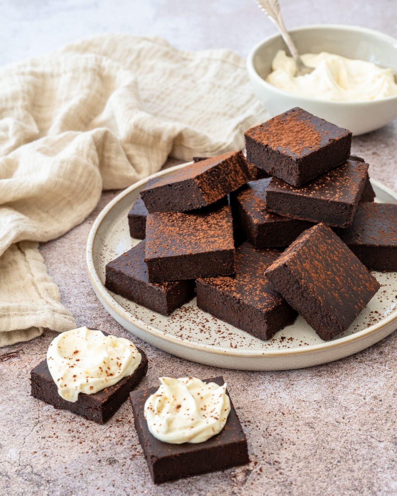 Décadent gâteau de style brownies coupés en carrés, déposés dans une assiette et saupoudrés de cacao