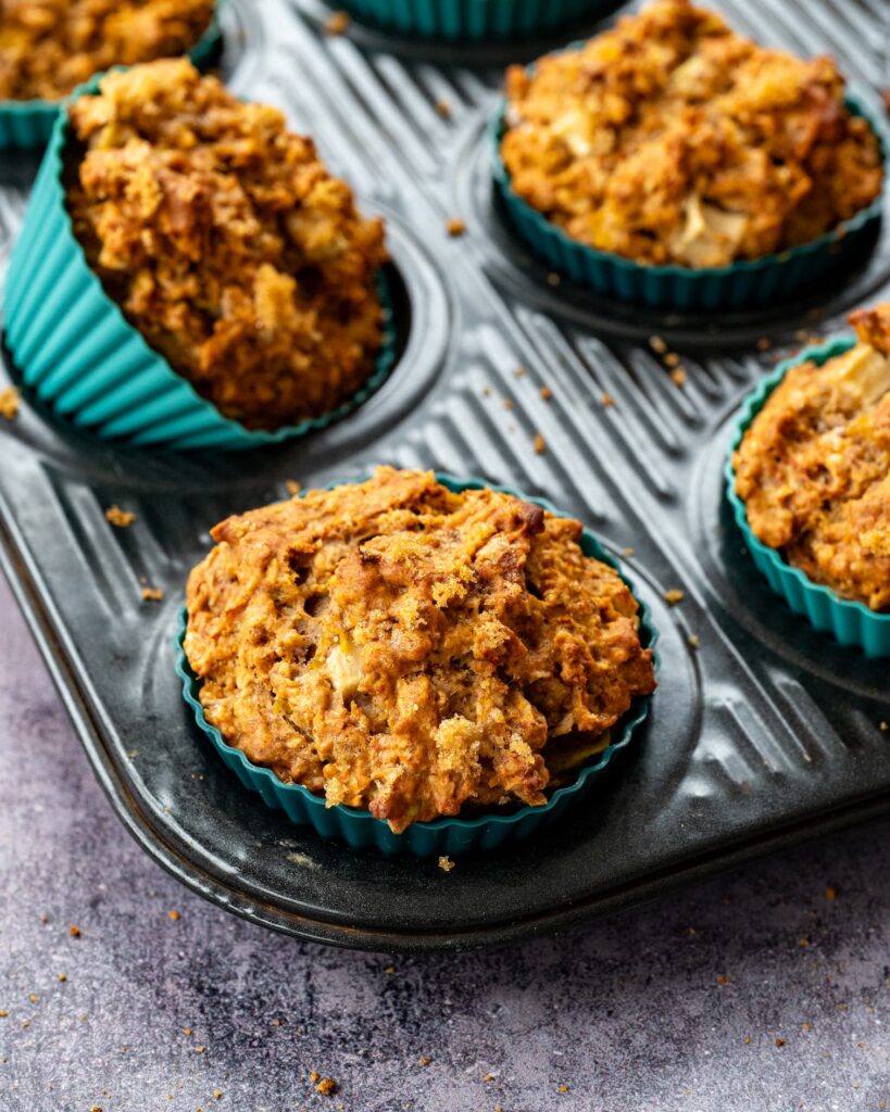 Muffins pommes, citrouille et gingembre dans un moule à muffins noir avec des caissettes de couleur turquoise