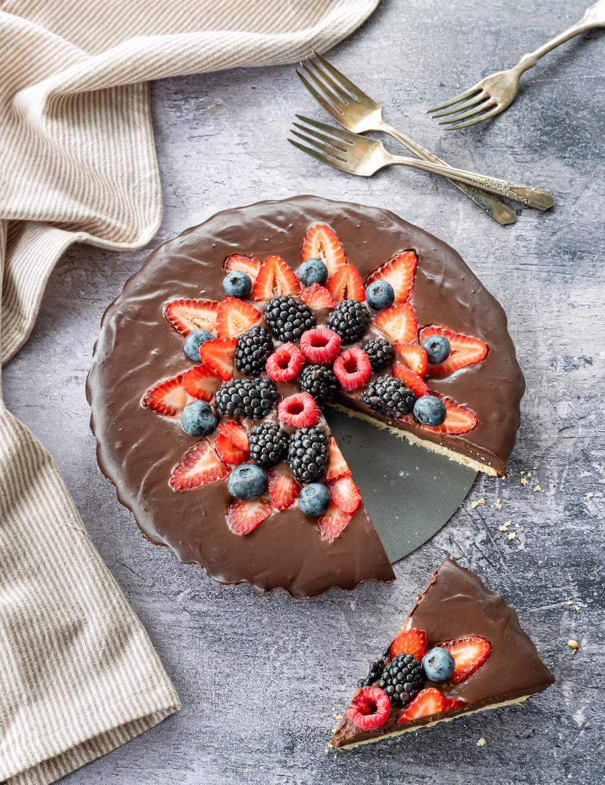 Belle tarte au chocolat décorée de fraises, framboises et bleuets