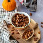 Graines de citrouille sucrées aux épices chaï déposées dans un petit bol accompagnées d'une petite citrouille et d'une tête de mort