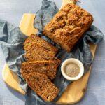 Pain aux bananes déposé sur une planche de bois, accompagné d'un linge bleu et de graines de chia