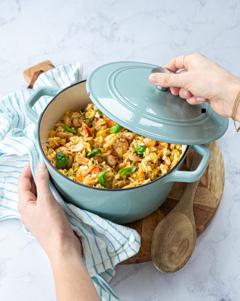 Casserole bleue pâle remplie d'un orzotto aux tomates séchées et crevettes.