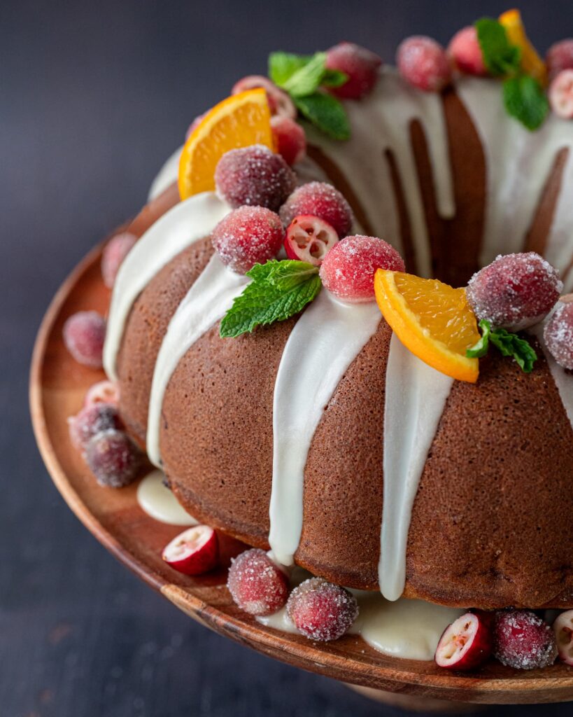 Magnifique gâteau Bundt décoré de canneberges givrées, de morceaux d'orange et de menthe fraîche