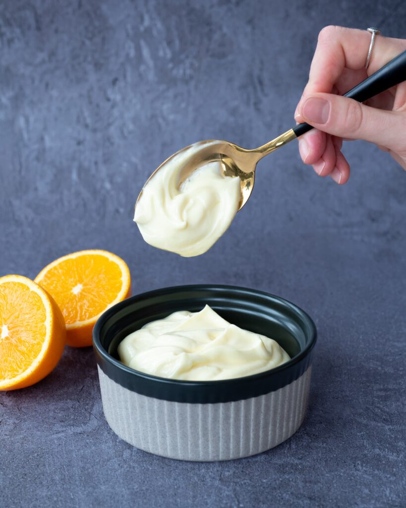 Bol de crémage à l'orange accompagnée d'une cuillère nappé de glaçage