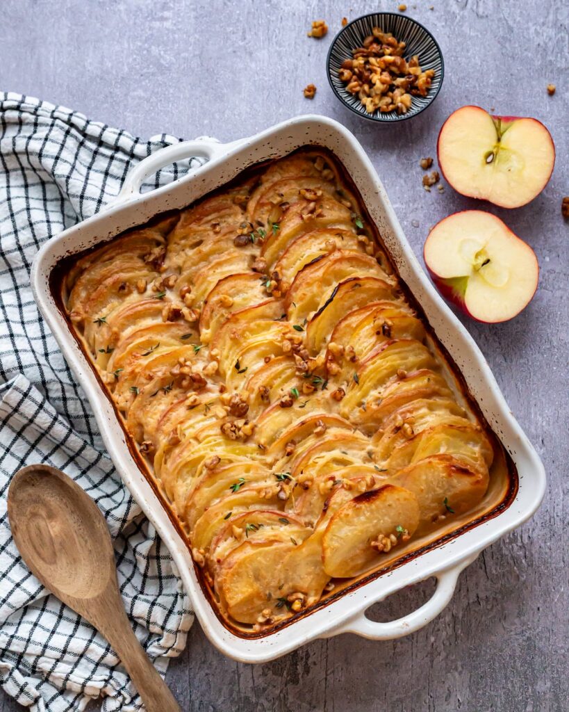 Délicieux gratin aux pommes de terre et pommes rouges, recouvert de gruyère et de noix caramélisées