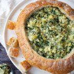 Généreuse trempette aux artichauts, épinards et kale servie dans une mie de pain rond