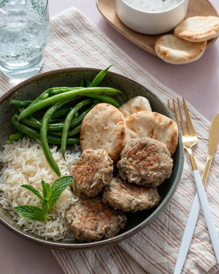 Boulettes de keftas au poule dans une assiette verte et accompagnés de riz blanc, de haricots verts et de mini pains naan