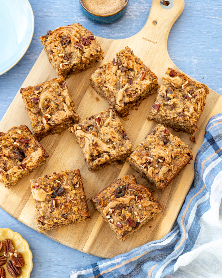 Gruau cuit au four aux bananes, beurre d'arachide et chocolat coupé en 9 morceaux et déposés sur une planche de bois