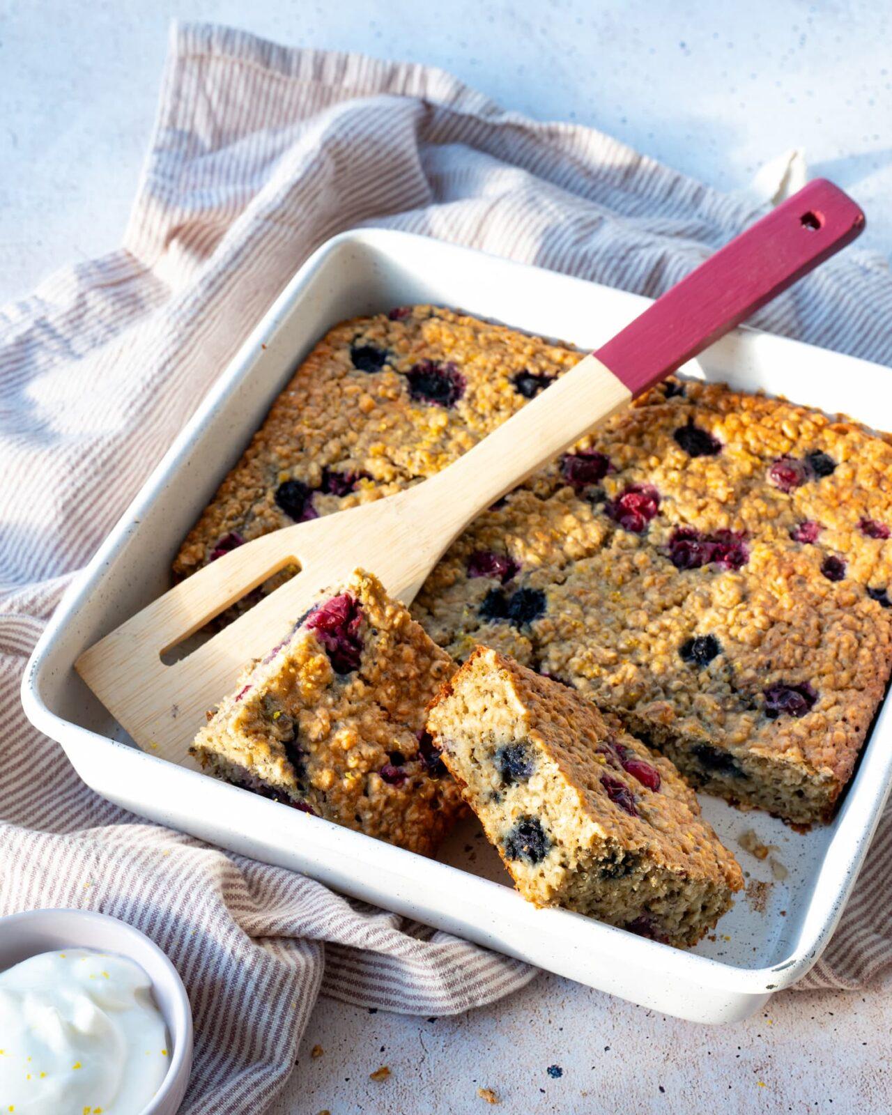 Un gruau style gâteau aux petits fruits présenté dans un moule blanc carré déposé sur un ligne ligné blanc et brun