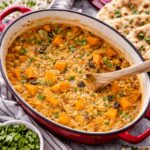Mijoté de pois chiches à l'indienne servi dans une cocotte rouge et accompagné de riz, de pain naan et de coriandre