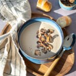 Crème de champignons déposée dans un bol bleu, et garnit de champignons tranchés et poêlés