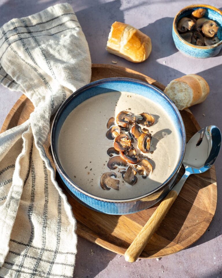 Crème de champignons déposée dans un bol bleu, et garnit de champignons tranchés et poêlés