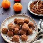 Truffes aux dattes et clémentines déposées dans une assiette beigne, accompagnées de 3 clémentines