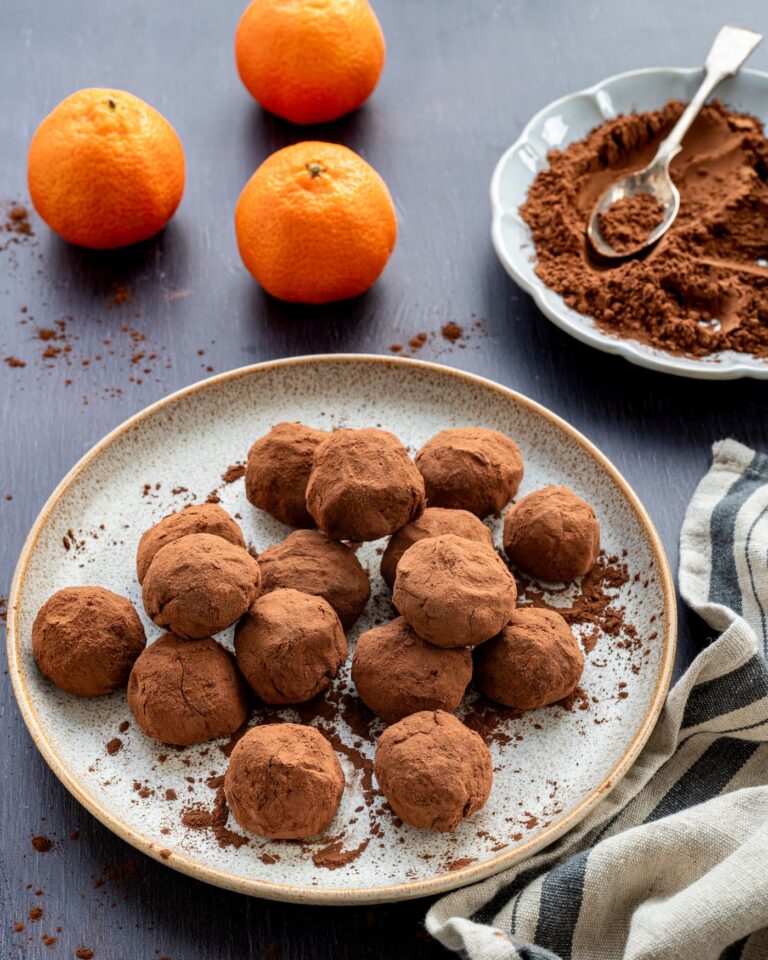 Truffes aux dattes et clémentines déposées dans une assiette beigne, accompagnées de 3 clémentines