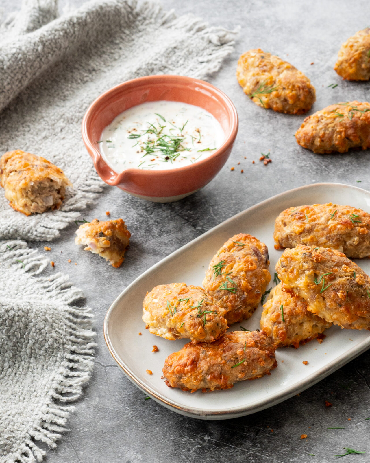 Bâtonnets croustillants au thon et au fromage déposés sur une assiette grise, et accompagnés d'une sauce à base de yogourt grec